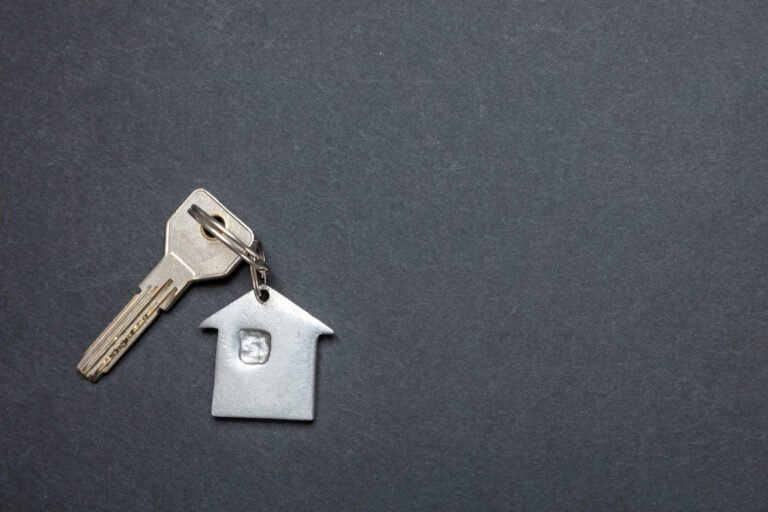 House key with silver keychain shaped like a home on dark background